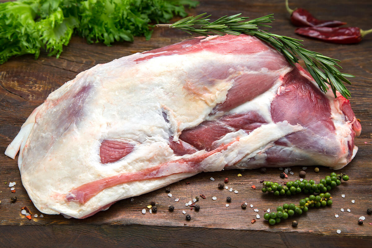 Pezzo di carne di pecora da cuocere su tagliere di legno