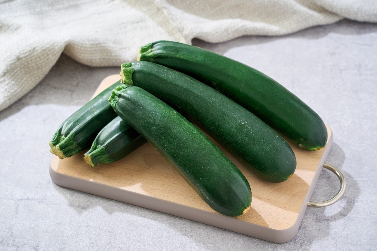 Tagliere di legno con zucchine scure