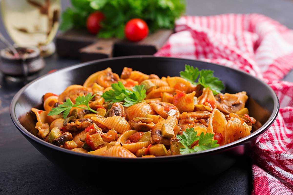Piatto con pasta condita con sugo di pomodoro, carne e funghi