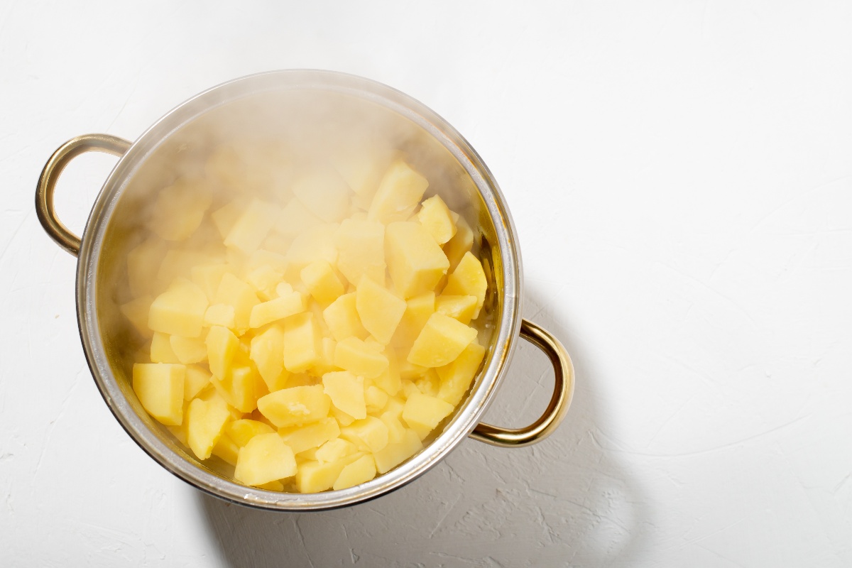 Vista dall'alto pentola con patate a tocchetti lessate e vapore che si solleva