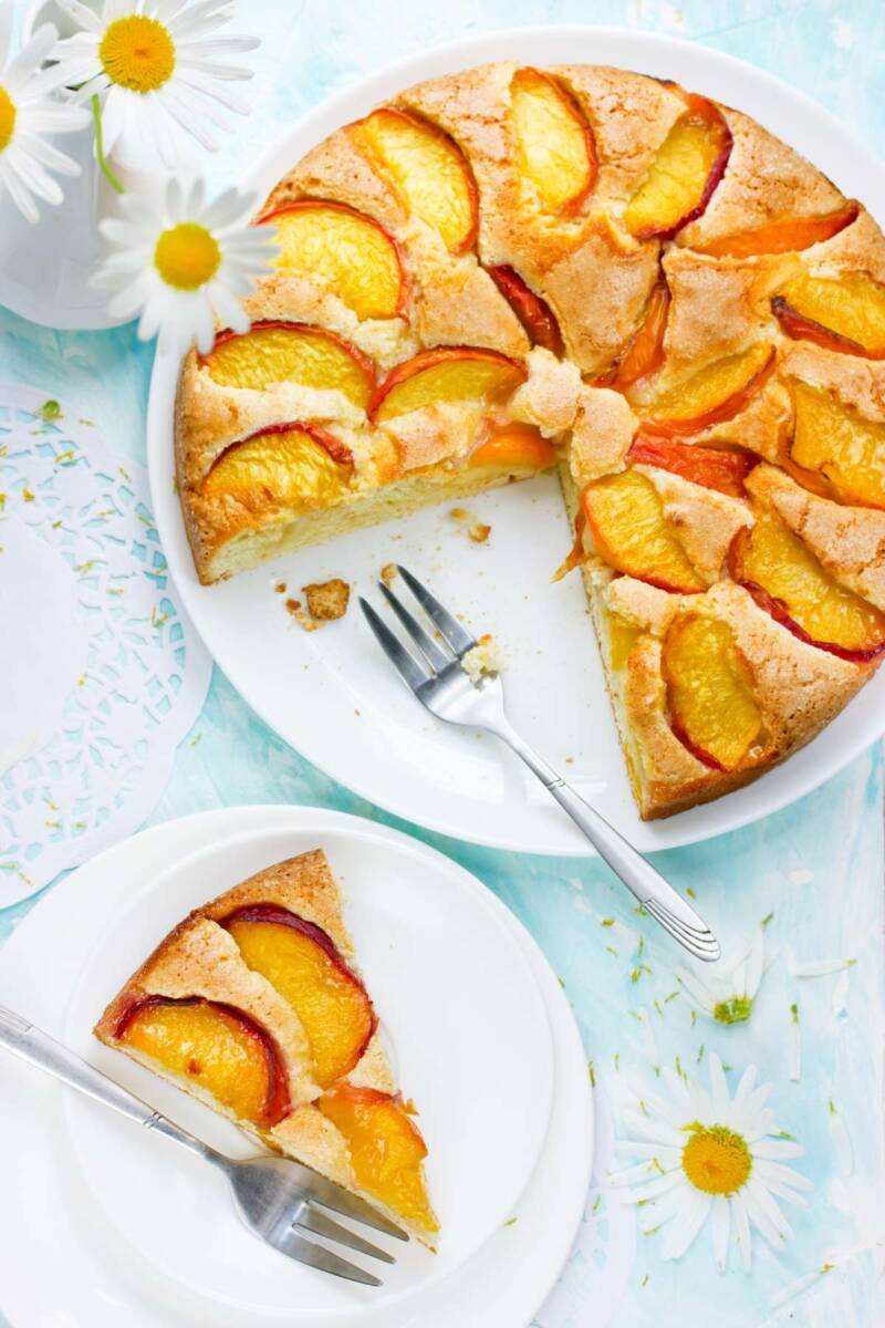 Piatto con torta alle pesche a cui manca una fetta messa su un piatto vicino