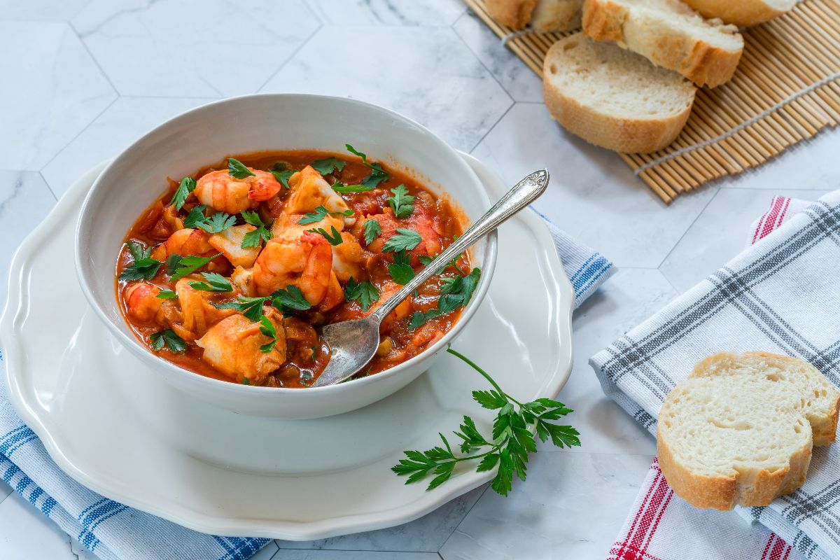 Piatto con zuppa di pesce in cui si vedono i gamberi