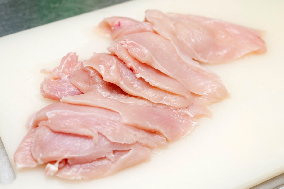 Petto di pollo a fette su tagliere bianco