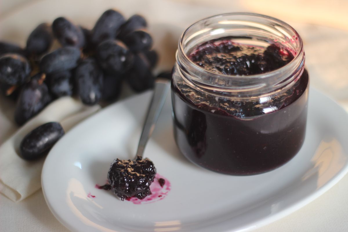 Vasetto di marmellata di uva con cucchiaino colmo della stessa