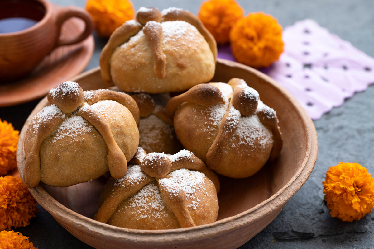 Ciotola con panini decorati con croce di impasto e zucchero a velo noti come pan de muertos