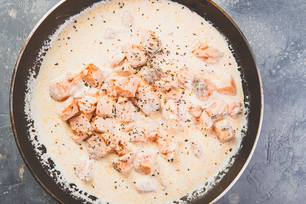 Vista dall'alto padella con sugo a base di panna e salmone