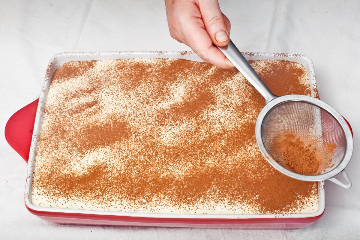 Aggiunta cacao amaro con piccolo setaccio a teglia di tiramisù
