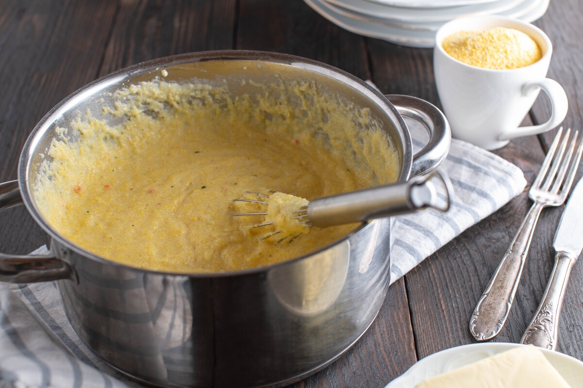 Pentola con polenta appena fatta e frusta per mescolare all'interno