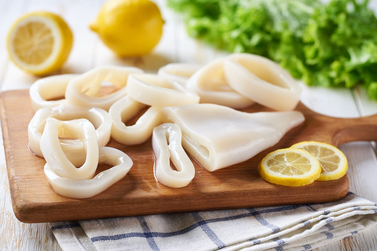 Tagliere di legno con calamari tagliati ad anelli e limone