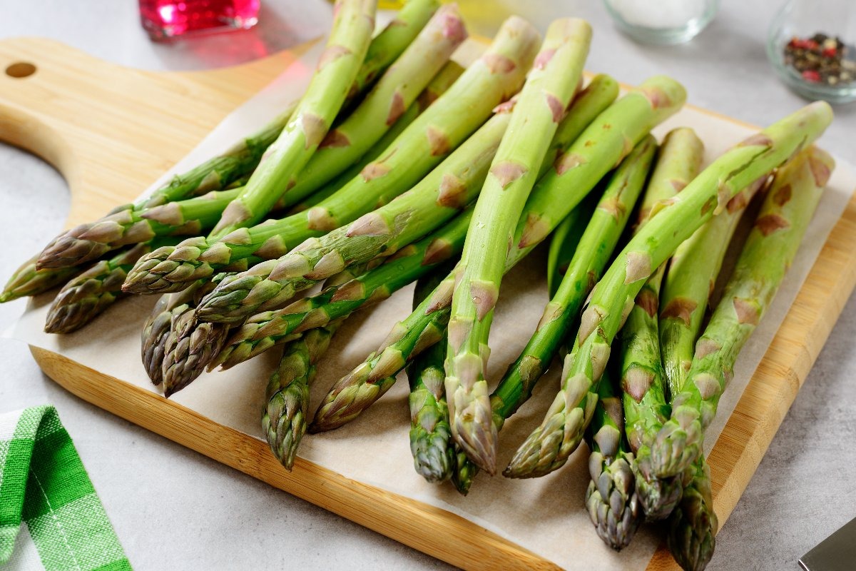 Tagliere di legno con asparagi freschi