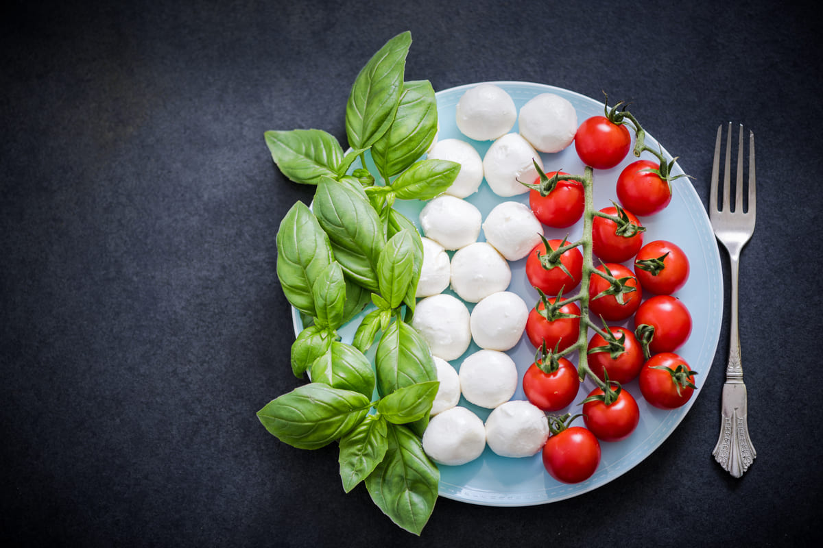 Piatto con basilico, mozzarella e pomodoro disposti a ricreare la bandiera italiana