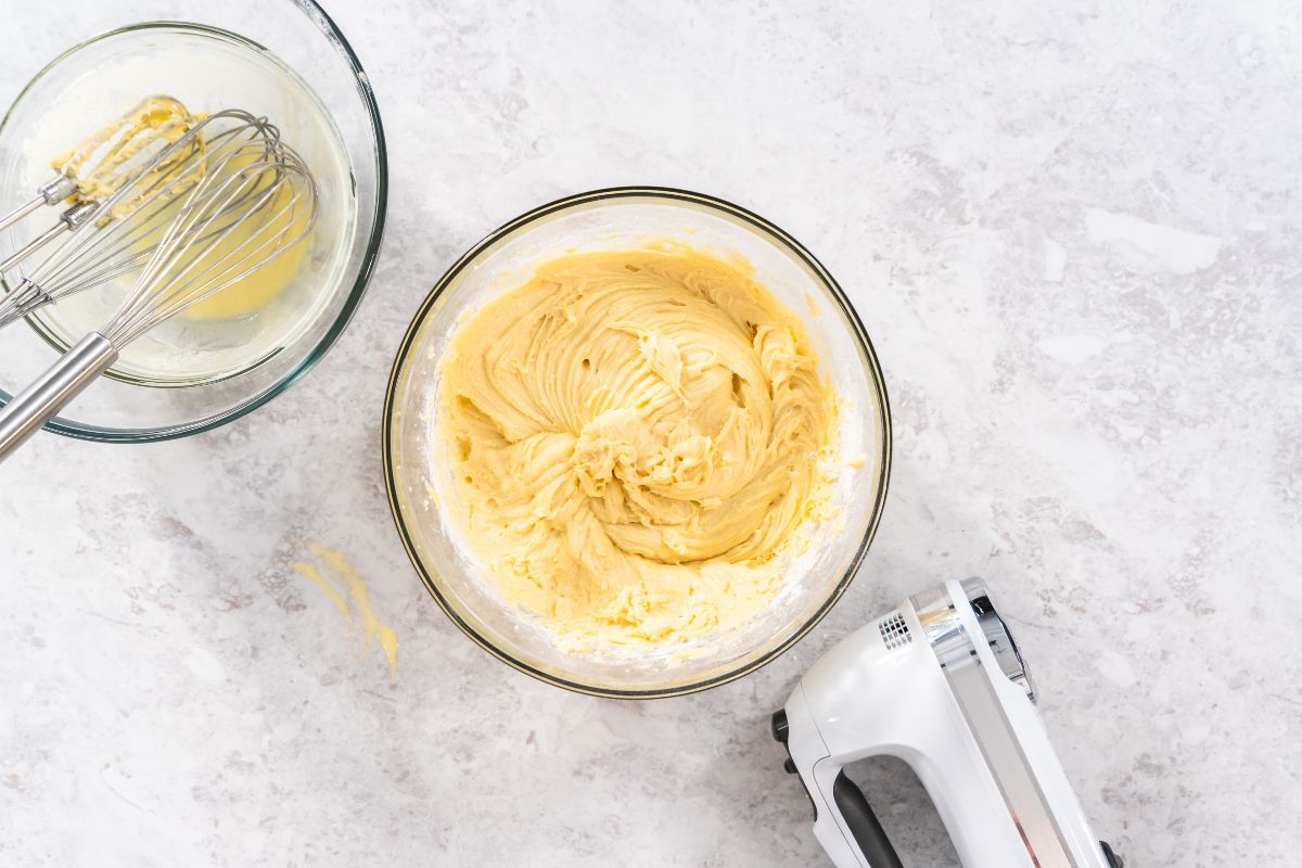 Vista dall'alto ciotola con impasto per torta e vicino fruste elettriche