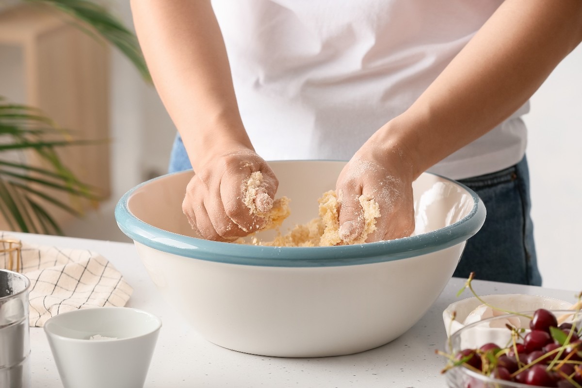 Mani che lavorano impasto torta nella ciotola