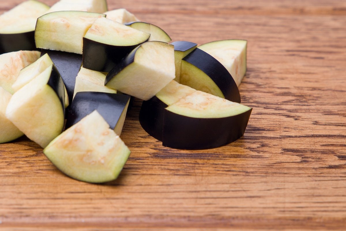 Tagliere di legno con melanzane tagliate a dadini