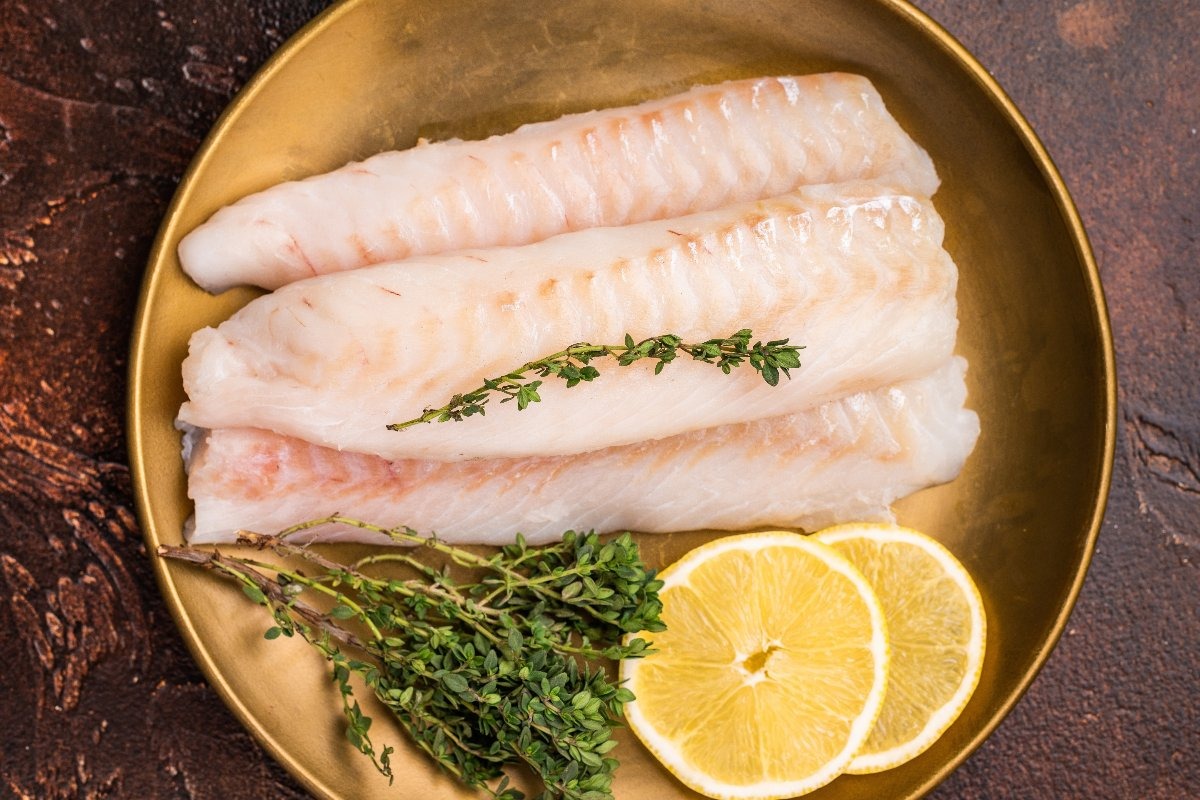 Filetti di merluzzo fresco su piatto con timo e limone