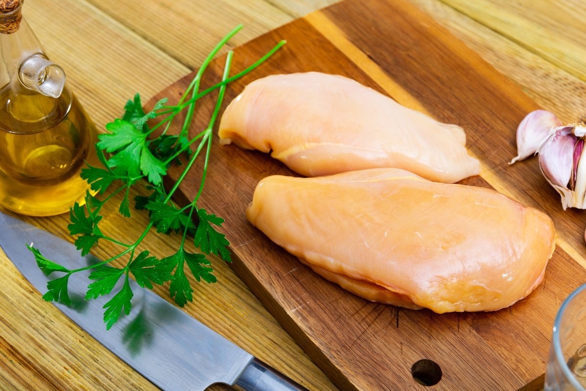 Petti di pollo interi su tagliere di legno
