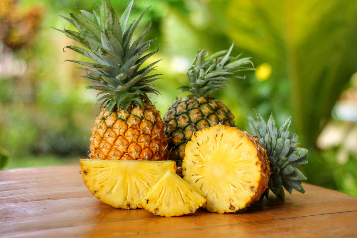 Frutto di ananas intero accanto a una metà tagliata.