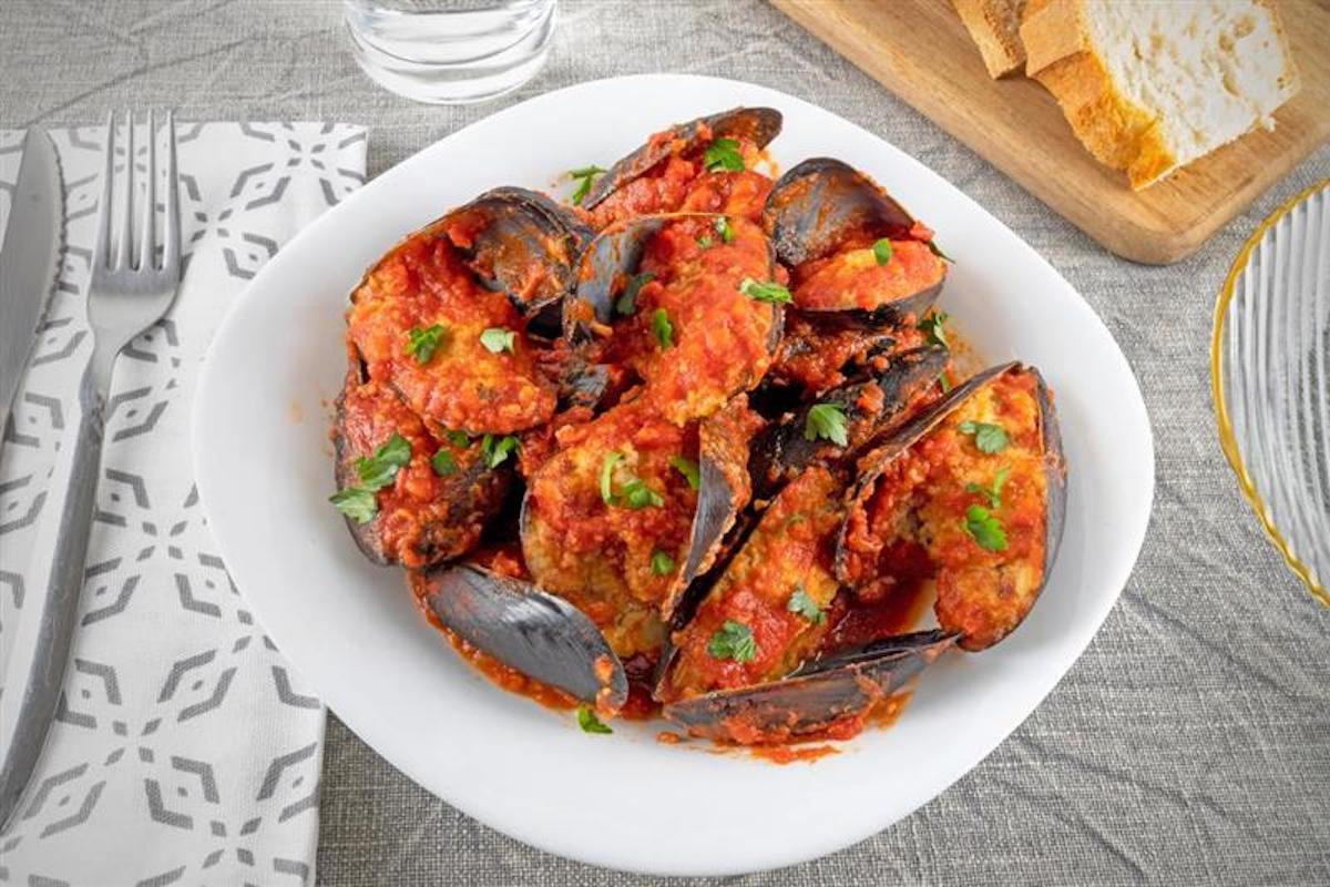 Piatto di cozze ripiene con sugo di pomodoro e prezzemolo
