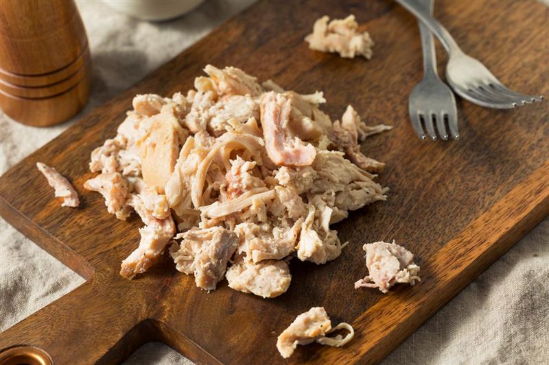 Pollo sfilacciato su tagliere di legno