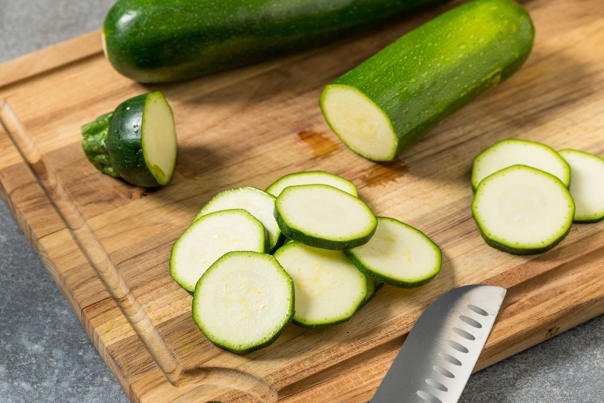 Tagliere di legno con zucchine tagliate a rondelle sottili