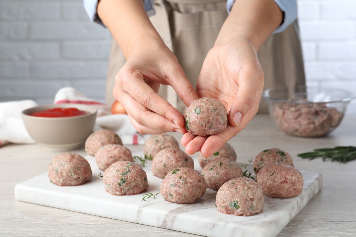 Mani di donna che preparano polpette di carne