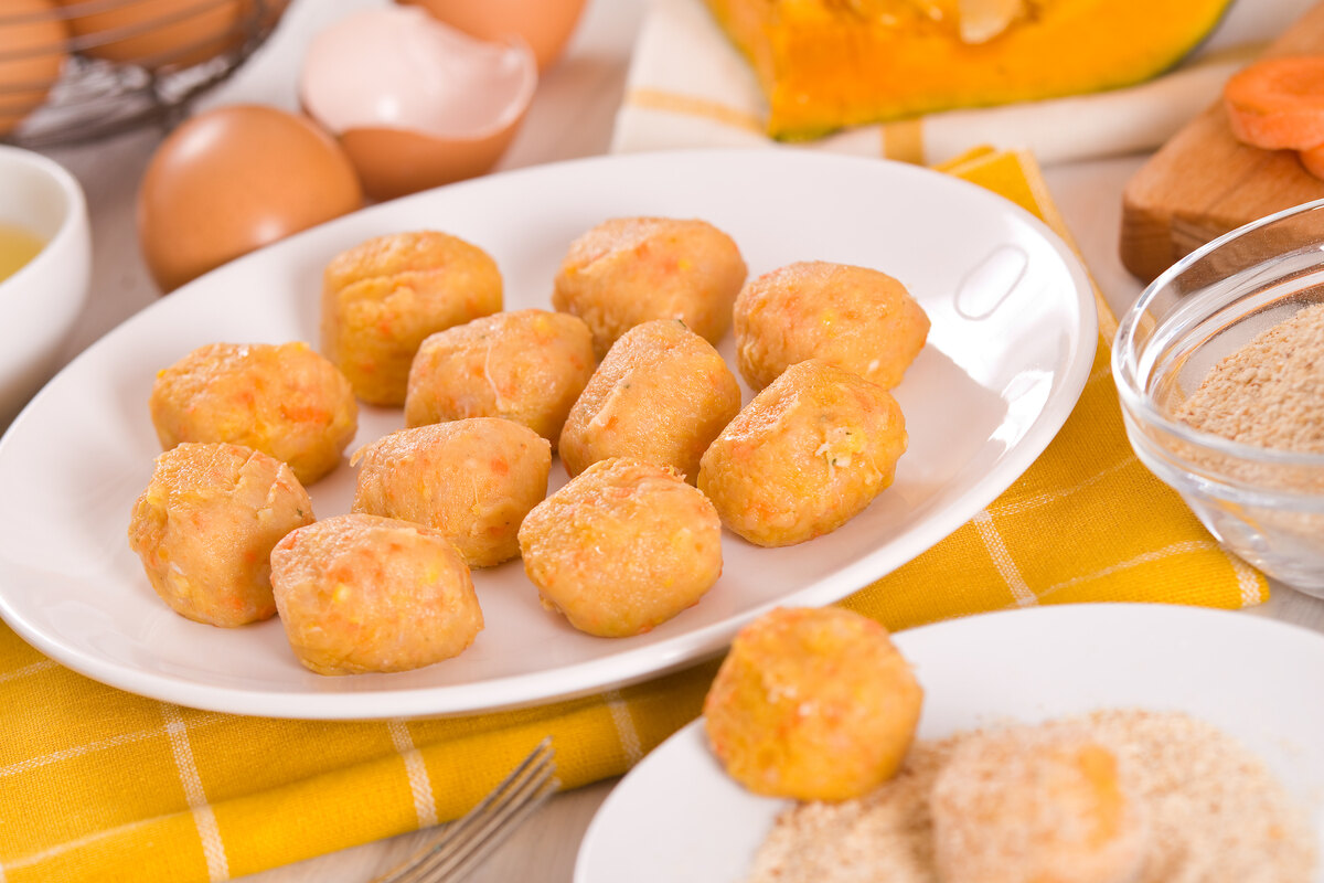 Piatto bianco con polpette di zucca da passare nel pane grattugiato e cuocere