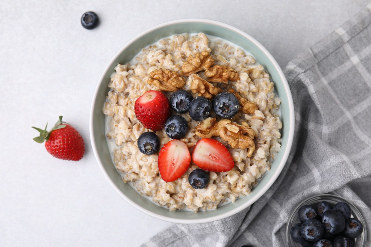 Vista dall’alto di una ciotola di porridge con noci, fragole e mirtilli.