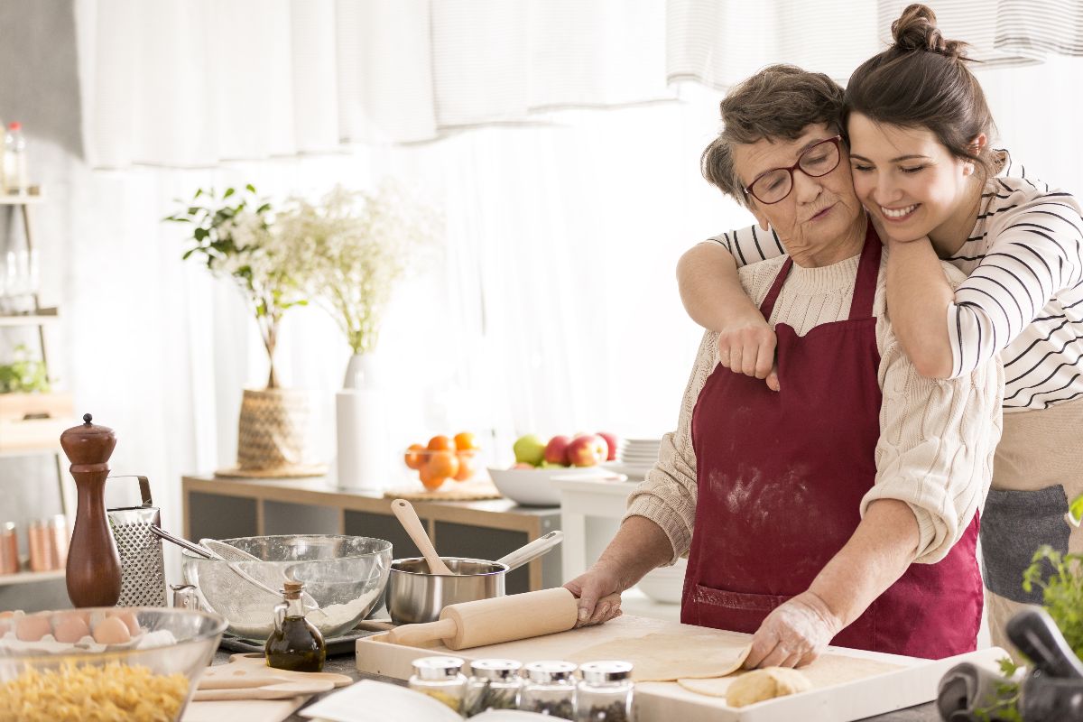 Nonna e nipote in cucina mentre preparano un dolce seguendo la ricetta di famiglia.