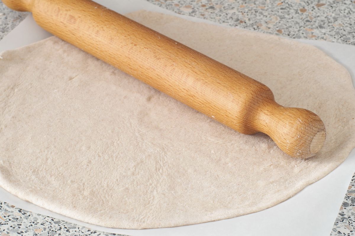 Pasta stesa con mattarello su carta forno