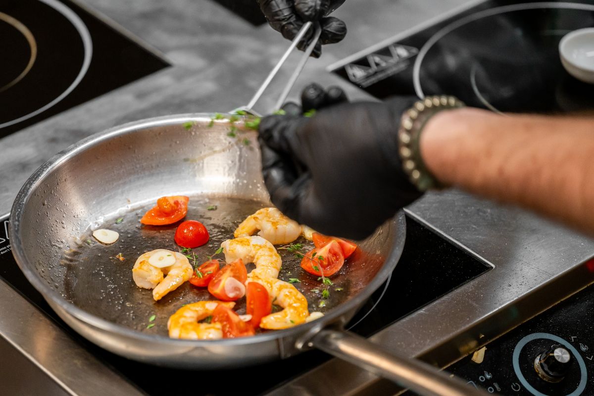 Padella sul fuoco con mazzancolle e pomodorini in cottura
