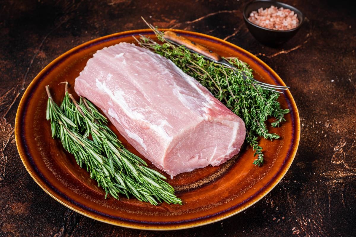 Piatto con lonza di maiale ed erbe aromatiche ancora da cuocere