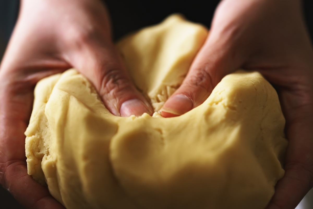 Mani che mostrano la consistenza della pasta frolla