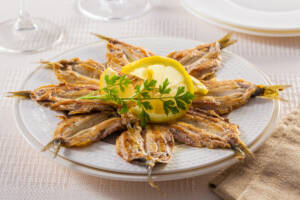 Piatto di alici fritte condite alla scapece con fetta di limone al centro