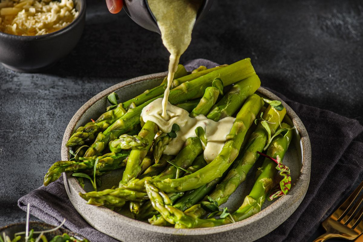 Salsa a base di uova e senape versata su asparagi lessati