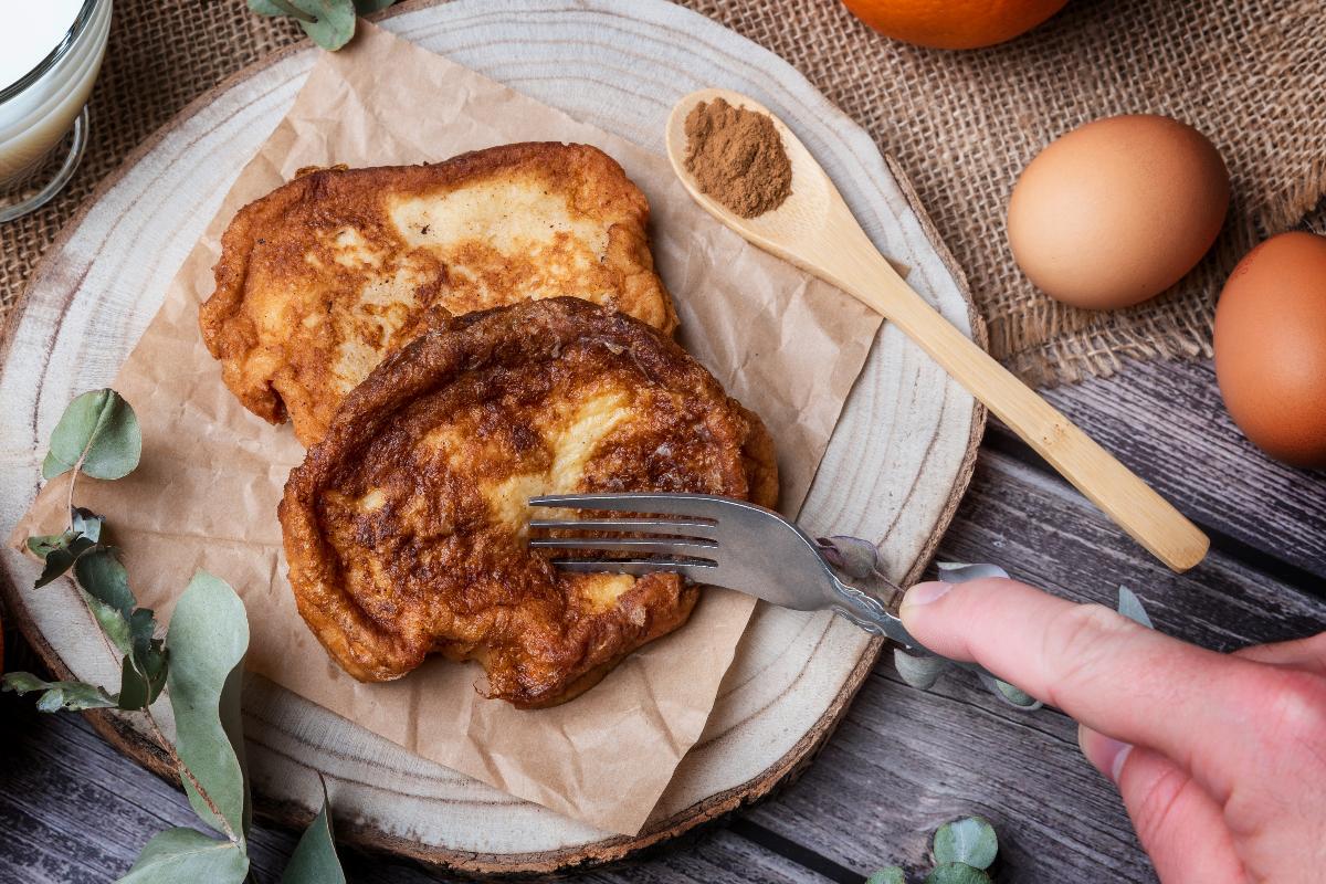 Vista dall'alto forchetta nell'atto di tagliare le torrijas, fette di pane ammollate nel latte, passate nelle uova e fritte