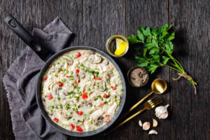 Padella con pollo, peperoni, piselli, funghi e panna