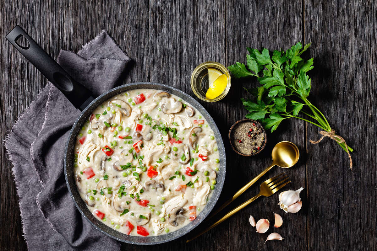Padella con pollo, peperoni, piselli, funghi e panna