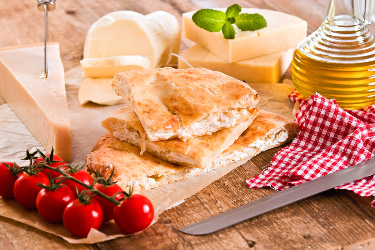 Focaccia tipo pizzolo siciliano farcita con formaggio e attorno vari tipi di formaggio