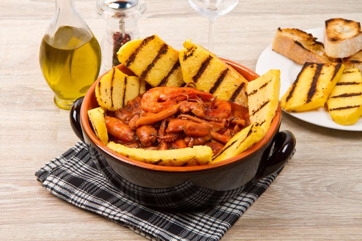 Ciotola di terracotta con zuppa di pesce e crostini di polenta grigliata
