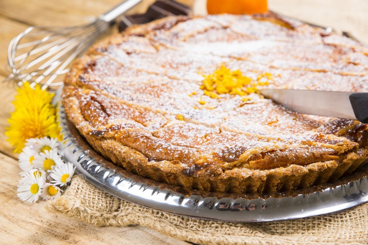 Coltello che taglia torta tipo crostata chiusa con zucchero a velo