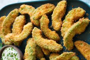 Fette di avocado impanato e fritto su piatto nero