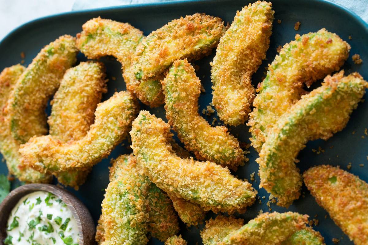 Fette di avocado impanato e fritto su piatto nero