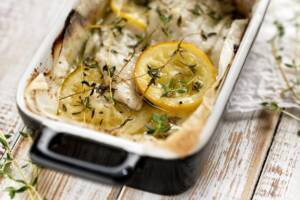 Pirofila di ceramica con pesce cotto al forno con limone e timo