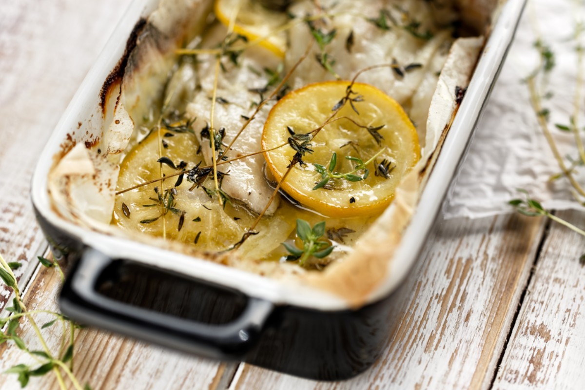 Pirofila di ceramica con pesce cotto al forno con limone e timo