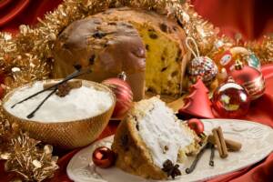 Fetta di panettone con crema al mascarpone vicino a panettone intero e ciotola con crema