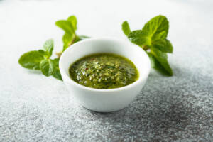 Ciotola con salsa alla menta e foglie di menta sullo sfondo