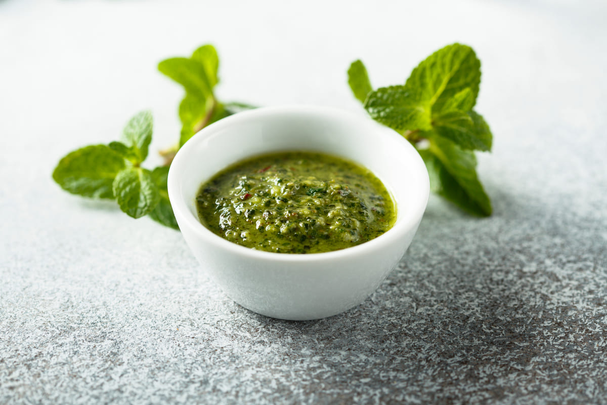 Ciotola con salsa alla menta e foglie di menta sullo sfondo