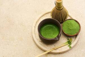 Vista tagliere in legno con ciotola, frustino e tè matcha in polvere