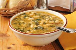 Piatto di zuppa rustica con patate, fagioli e cicoria