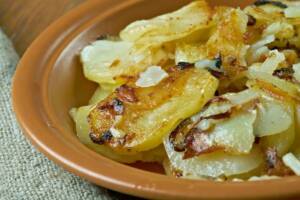 Piatto di terracotta con patate a fette e cipolle